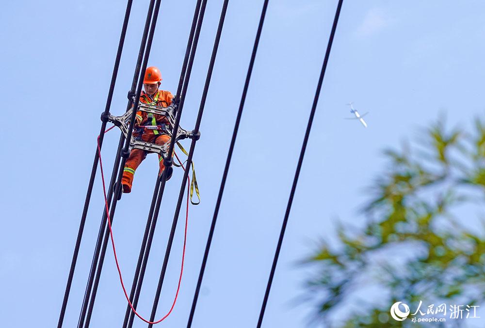 3月11日，在浙江省諸暨市河上鎮(zhèn)，浙江省送變電工程有限公司檢修人員在高空的導(dǎo)線上進行線路檢修維護。人民網(wǎng) 章勇濤攝