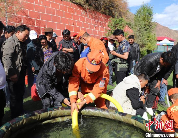 圖為森林消防員為護(hù)林員講解滅火裝備的使用方法?！〔际猩窒乐ш?duì) 供圖